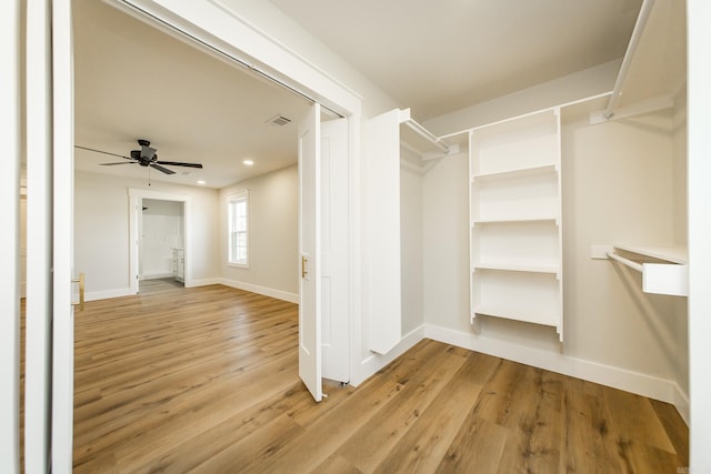 spacious closet with light wood finished floors, visible vents, and ceiling fan