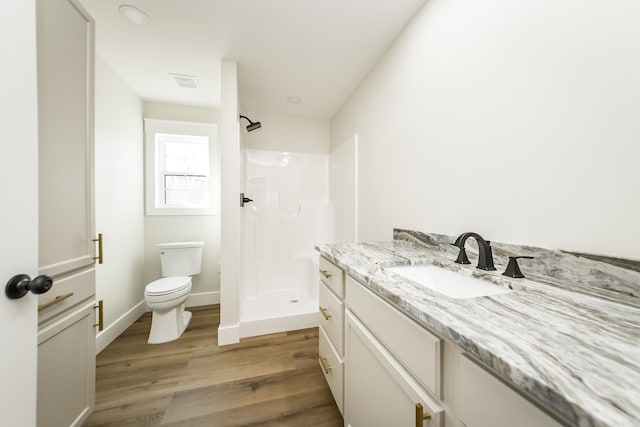 bathroom featuring visible vents, toilet, a stall shower, wood finished floors, and vanity