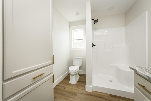 full bathroom featuring toilet, wood finished floors, visible vents, and a stall shower