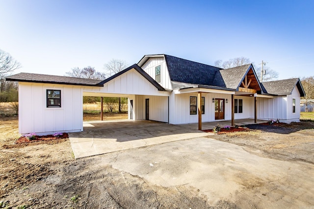 view of front of home featuring board and batten siding, a carport, roof with shingles, and driveway