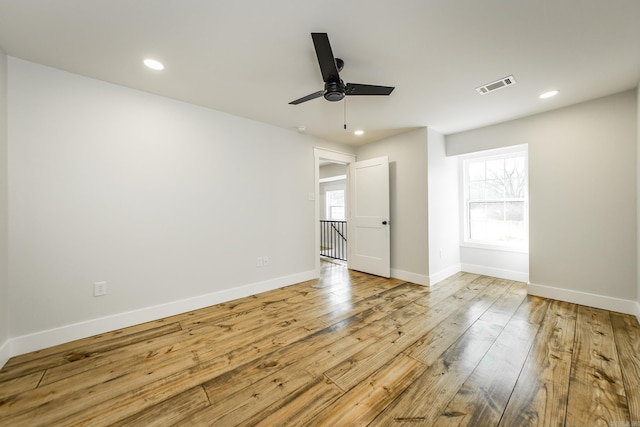 spare room featuring hardwood / wood-style flooring, a healthy amount of sunlight, visible vents, and ceiling fan