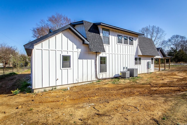 rear view of property featuring central AC unit, roof with shingles, and board and batten siding