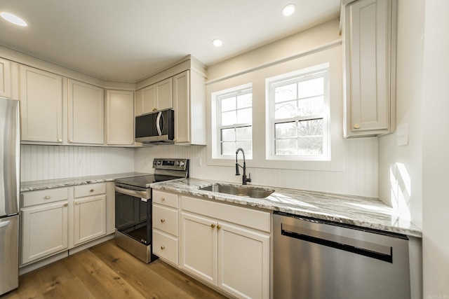 kitchen with dark wood-type flooring, light stone countertops, recessed lighting, stainless steel appliances, and a sink