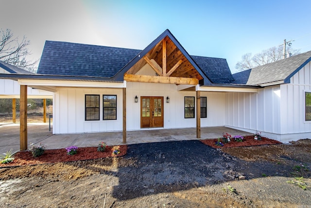 modern farmhouse featuring french doors, roof with shingles, board and batten siding, and a carport