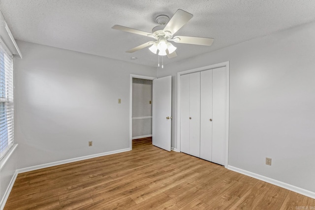 unfurnished bedroom with a closet, light wood-style flooring, a textured ceiling, and baseboards