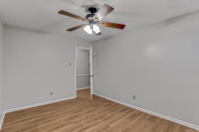 empty room featuring baseboards, a textured ceiling, light wood-style flooring, and a ceiling fan