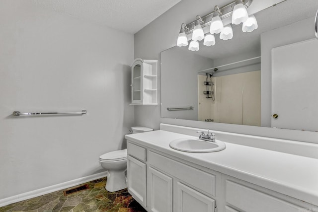 bathroom featuring walk in shower, baseboards, toilet, stone finish floor, and vanity