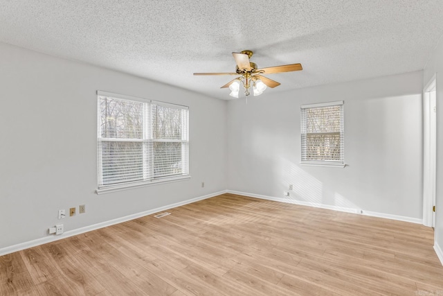 empty room with a wealth of natural light, baseboards, a ceiling fan, and light wood finished floors