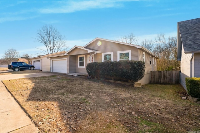 view of front of home featuring an attached garage, concrete driveway, and fence