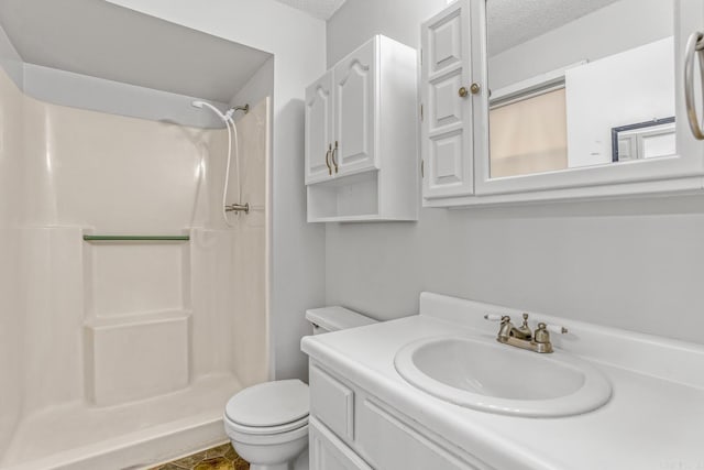 bathroom with a textured ceiling, walk in shower, vanity, and toilet