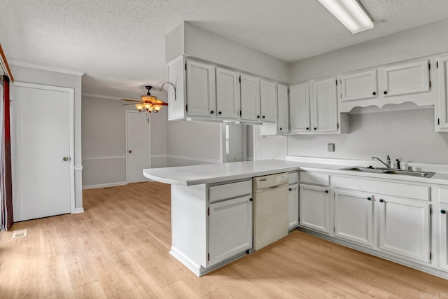 kitchen with a sink, light wood-style floors, dishwasher, and a peninsula