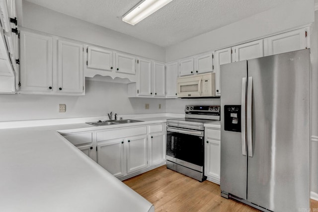 kitchen with a sink, appliances with stainless steel finishes, white cabinets, and light wood finished floors