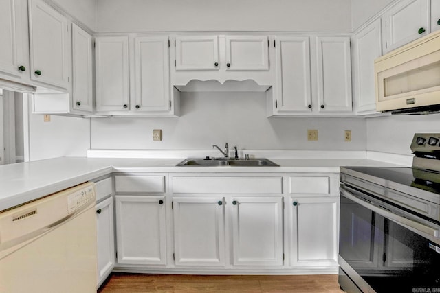 kitchen featuring white cabinets, white appliances, light countertops, and a sink