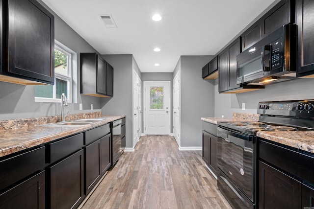 kitchen with baseboards, light wood-style flooring, a sink, black appliances, and light countertops