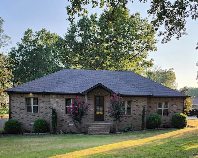 ranch-style house with brick siding, a shingled roof, and a front lawn