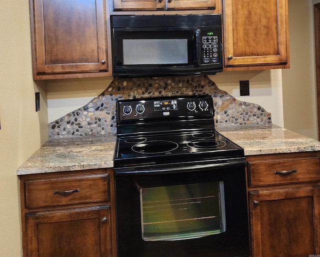 kitchen featuring light stone counters, decorative backsplash, and black appliances