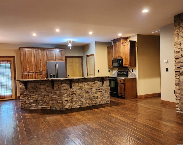 kitchen with a kitchen island, recessed lighting, black appliances, and dark wood-type flooring