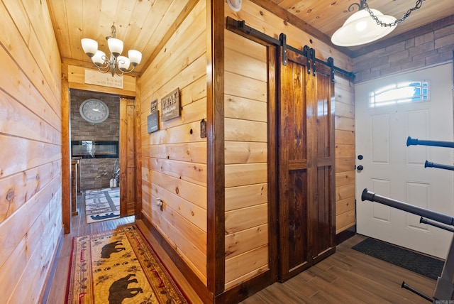 entryway featuring a chandelier, wooden walls, wood ceiling, and dark wood-style flooring