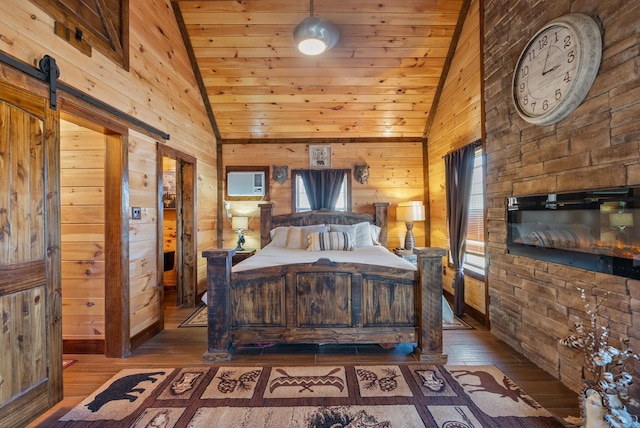 bedroom featuring wooden walls, multiple windows, a barn door, and hardwood / wood-style floors