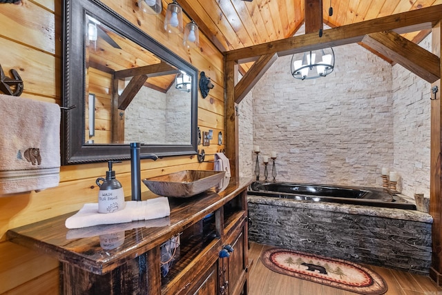 bathroom with a garden tub, lofted ceiling with beams, wood finished floors, wooden ceiling, and vanity