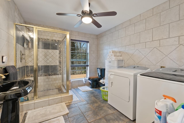 laundry area featuring stone tile flooring, washer and dryer, tile walls, and ceiling fan