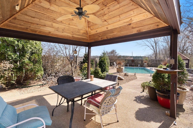 view of patio featuring outdoor dining space, a fenced backyard, a gazebo, a fenced in pool, and ceiling fan