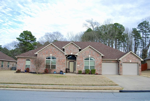 ranch-style house with concrete driveway, brick siding, a garage, and roof with shingles