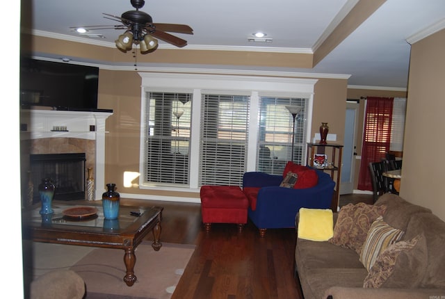 living room with a fireplace, wood finished floors, a ceiling fan, and ornamental molding