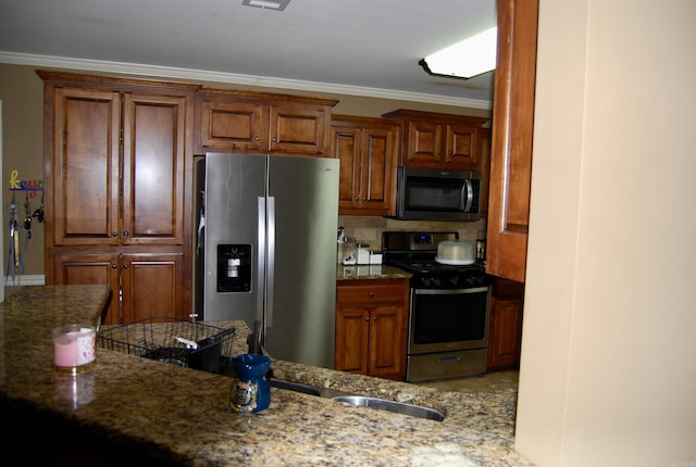 kitchen featuring decorative backsplash, crown molding, stone countertops, and appliances with stainless steel finishes