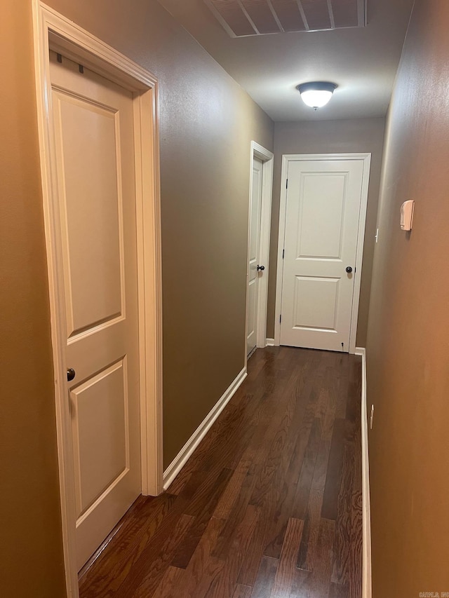 corridor featuring dark wood-type flooring and baseboards