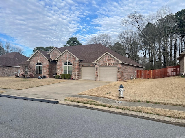 view of front facade featuring fence, a shingled roof, concrete driveway, a garage, and brick siding