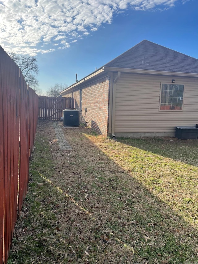 view of home's exterior with central air condition unit, a lawn, and a fenced backyard