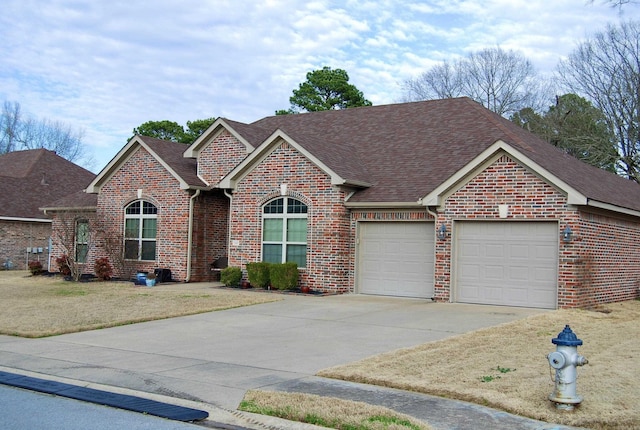 view of front facade with driveway, a front yard, a shingled roof, a garage, and brick siding