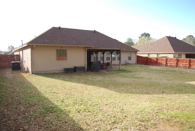 rear view of house featuring a yard, a patio, a fenced backyard, and a shingled roof