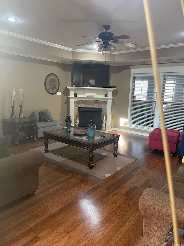 living area with a tile fireplace, wood finished floors, a ceiling fan, and ornamental molding