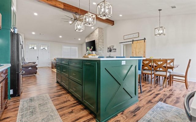 kitchen featuring vaulted ceiling with beams, green cabinets, a barn door, freestanding refrigerator, and a notable chandelier