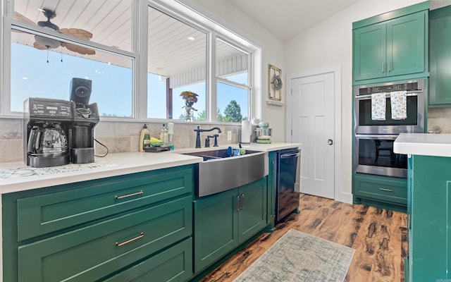 kitchen with stainless steel double oven, tasteful backsplash, light countertops, and a sink