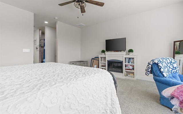 carpeted bedroom featuring visible vents, ceiling fan, baseboards, and a glass covered fireplace