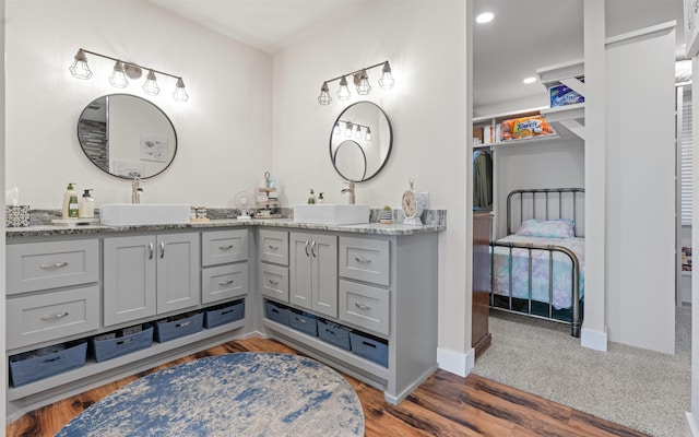 full bath featuring double vanity, wood finished floors, baseboards, and a sink