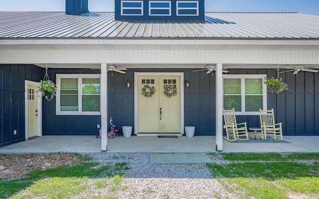 entrance to property featuring a porch, a ceiling fan, and metal roof