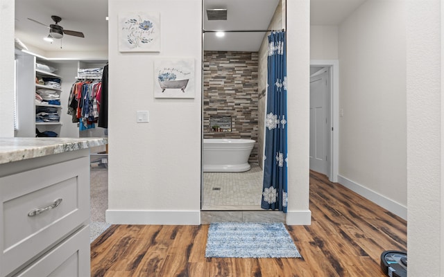 full bath with ceiling fan, wood finished floors, a shower with curtain, a freestanding tub, and vanity