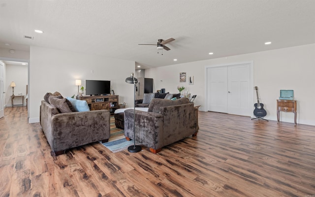 living area featuring visible vents, a textured ceiling, ceiling fan, and wood finished floors