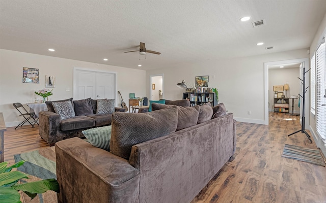 living area with visible vents, baseboards, wood finished floors, and a ceiling fan