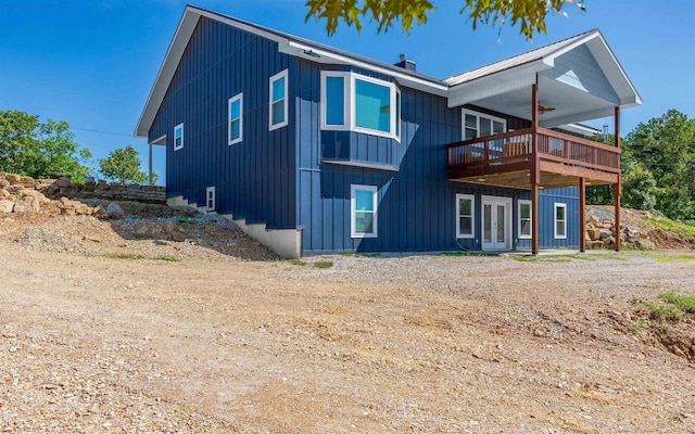 rear view of property featuring a deck, french doors, a chimney, and board and batten siding