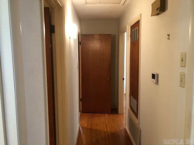 hall featuring visible vents, attic access, and wood finished floors