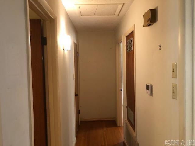 corridor with attic access and wood finished floors