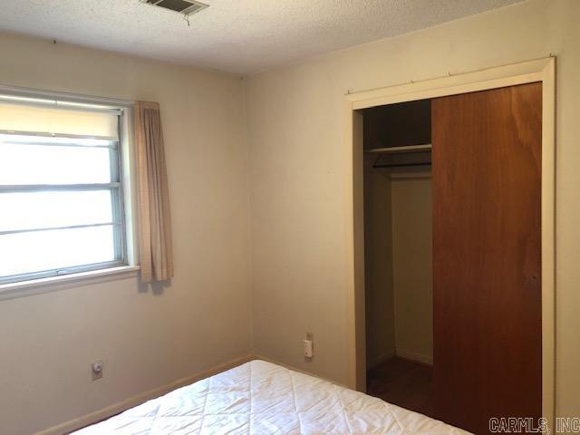 unfurnished bedroom featuring visible vents, a textured ceiling, and a closet