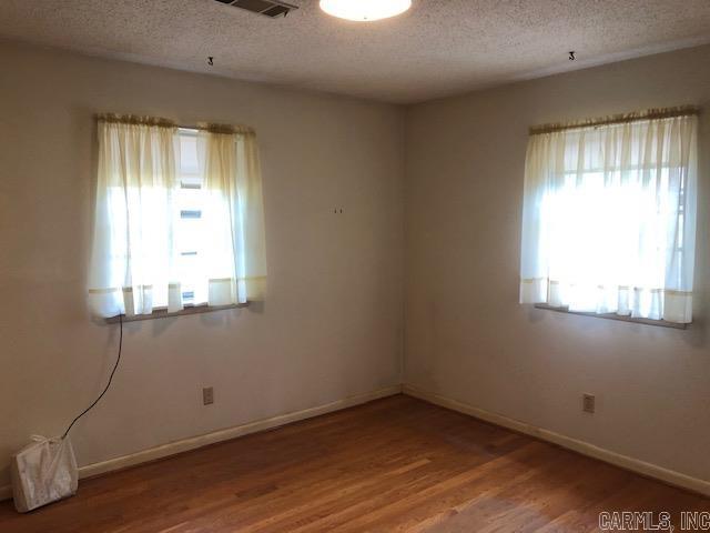 spare room featuring wood finished floors, baseboards, and a textured ceiling