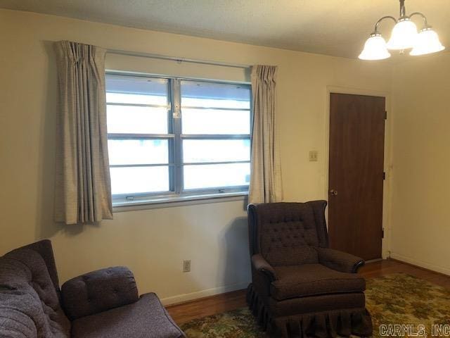 living area with baseboards, a notable chandelier, and wood finished floors