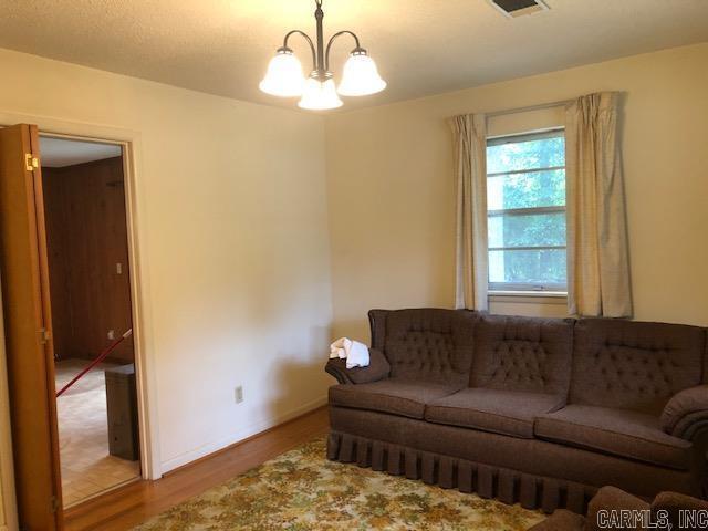 living area with baseboards, wood finished floors, visible vents, and a chandelier